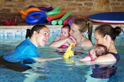 Teacher with babies in a swimming lesson, singing a song.